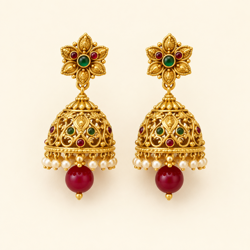 Pair of gold-tone jhumka earrings with red bead drops on an ivory background